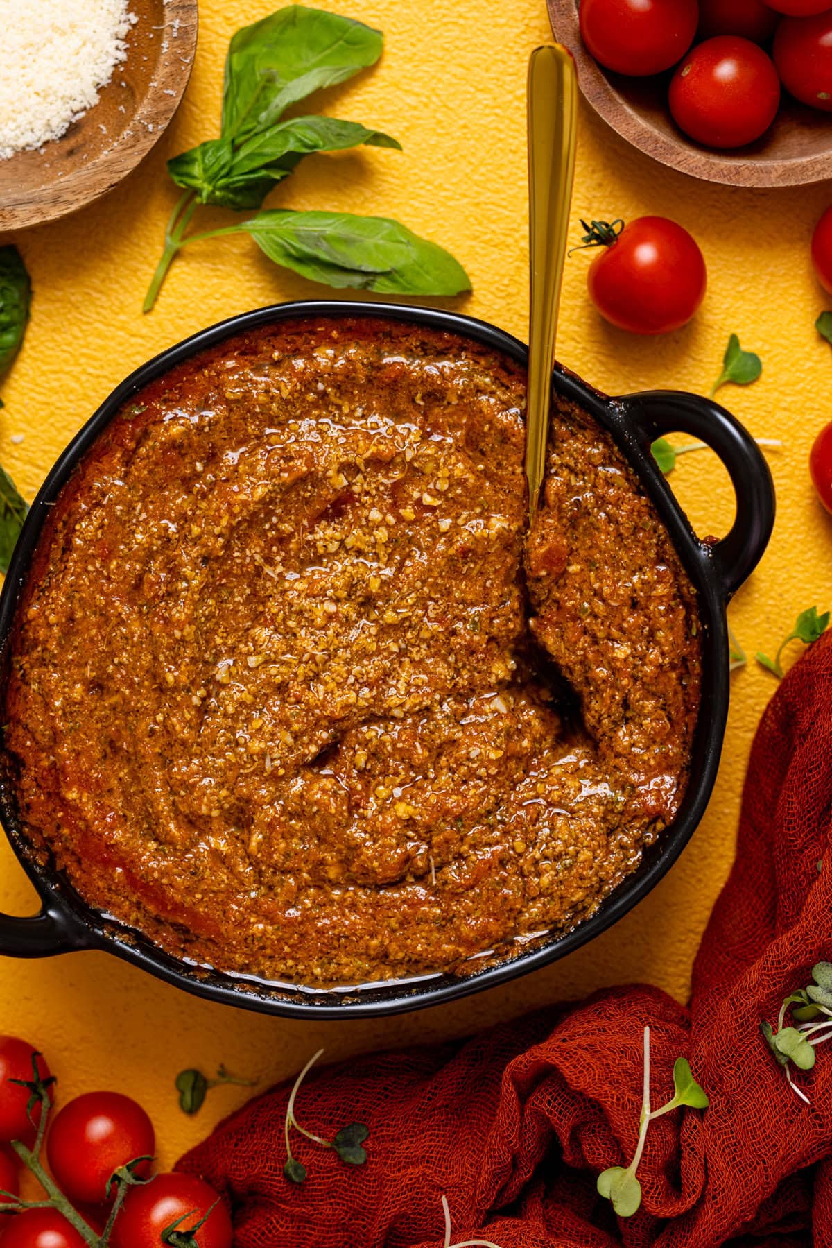 Tomato pesto in a black bowl with a spoon.