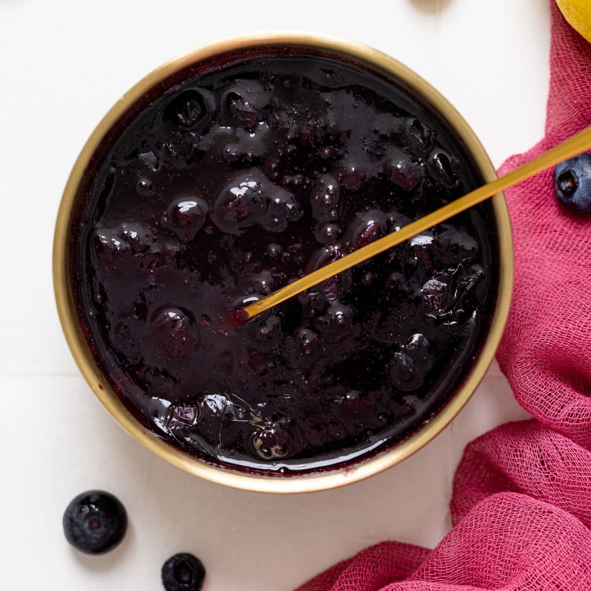 Up close shot of blueberry compote in a bowl with a spoon.