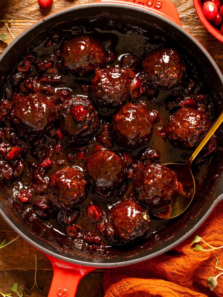 Up close shot of Cranberry BBQ Jerk meatballs with a gold spoon.