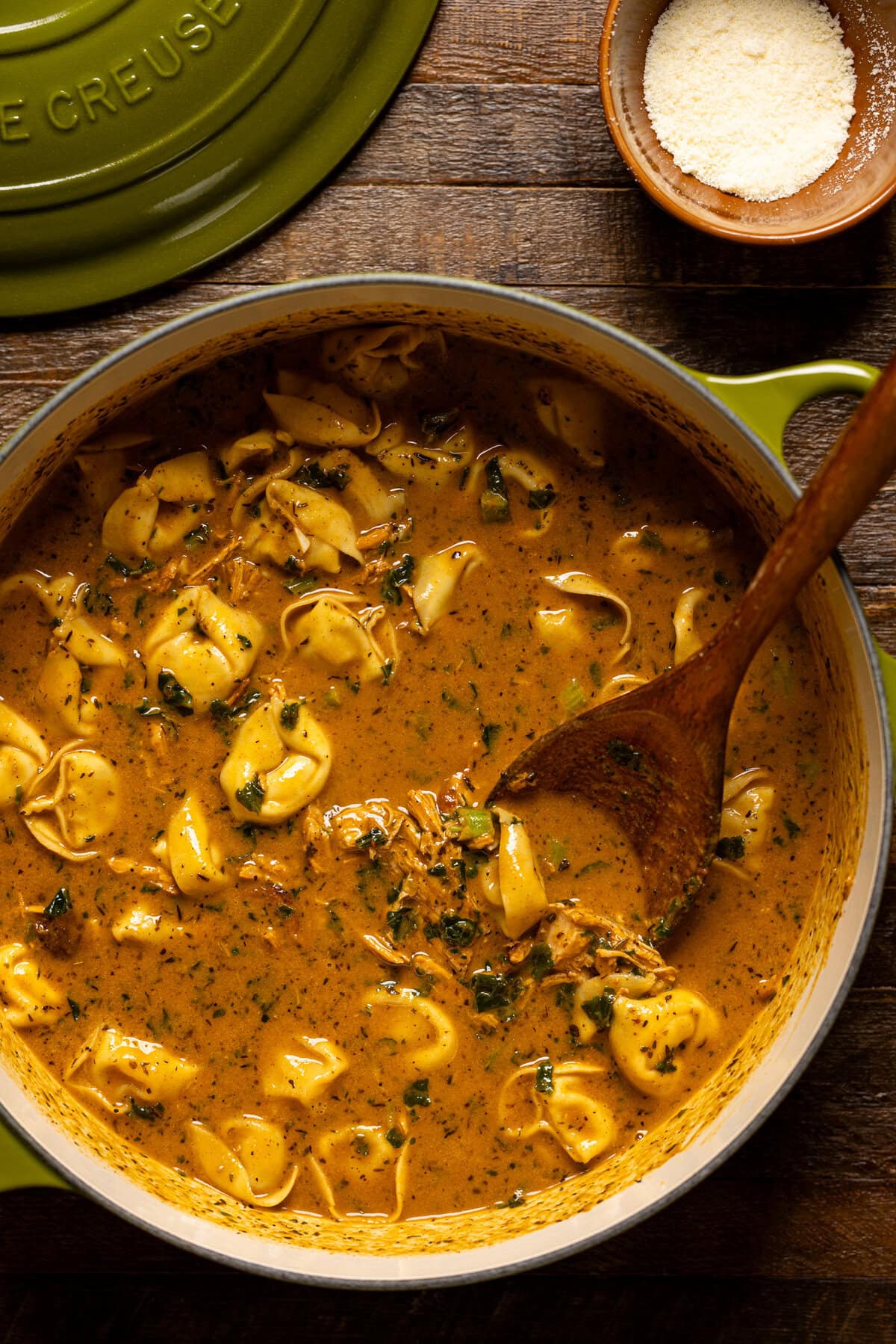 Blackened chicken tortellini soup in a green pot.