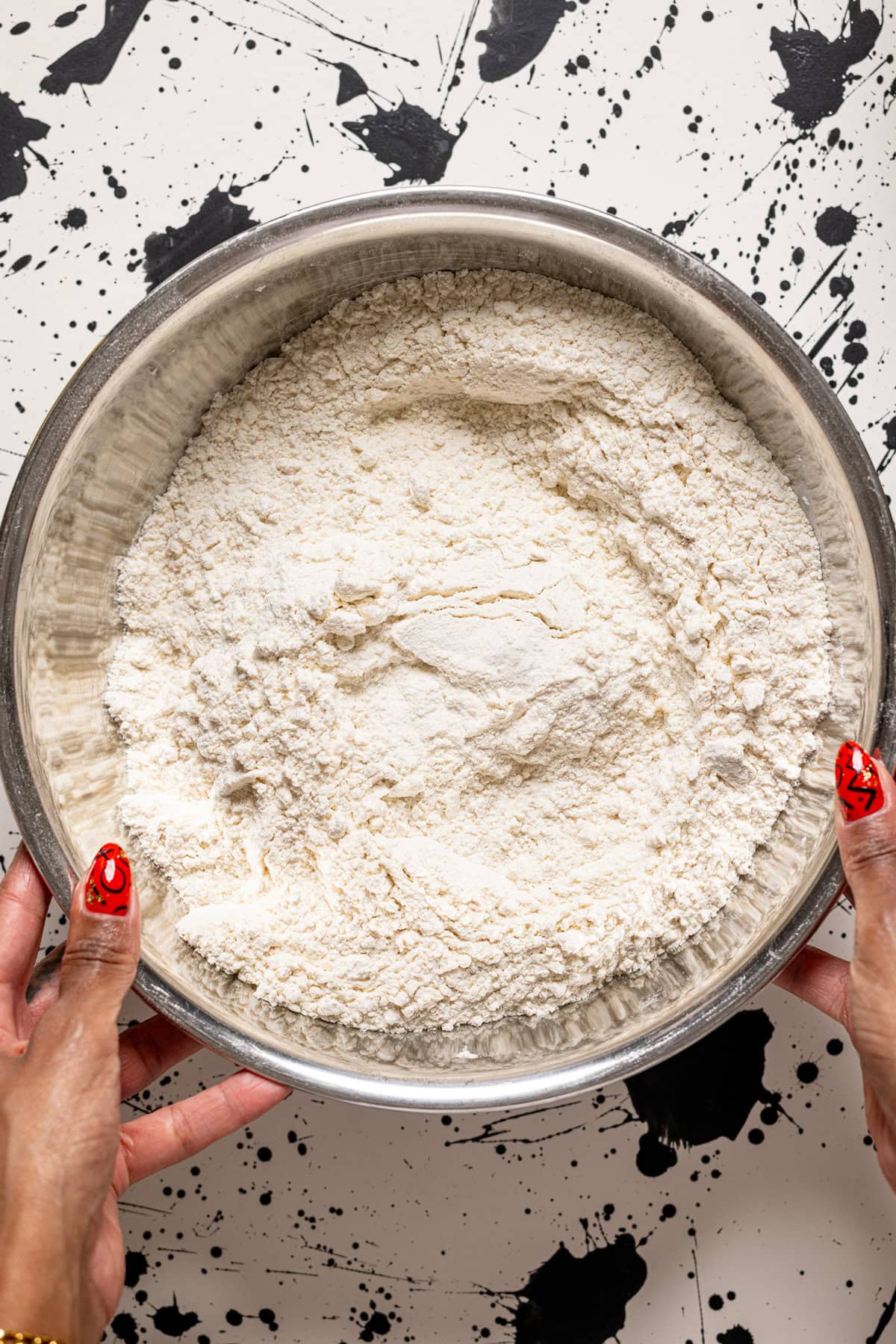 A silver bowl with flour and dry ingredients. 