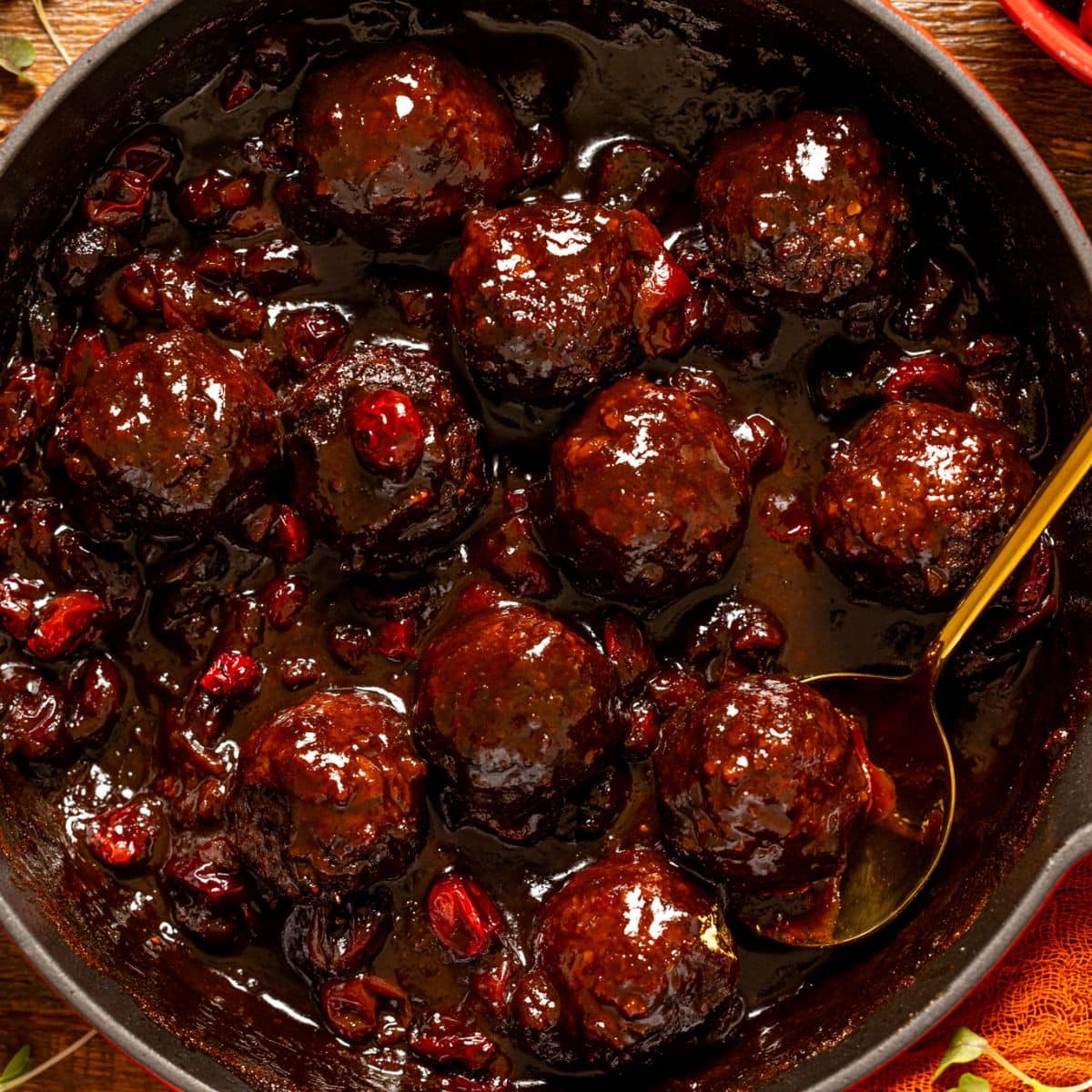 Up close shot of Cranberry BBQ Jerk meatballs with a gold spoon.