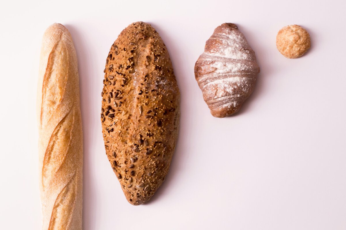 Different breads and baked goods on pink background.