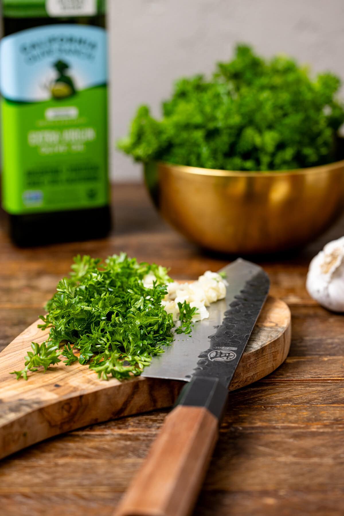 Chopped herbs on a cutting board with a knife.