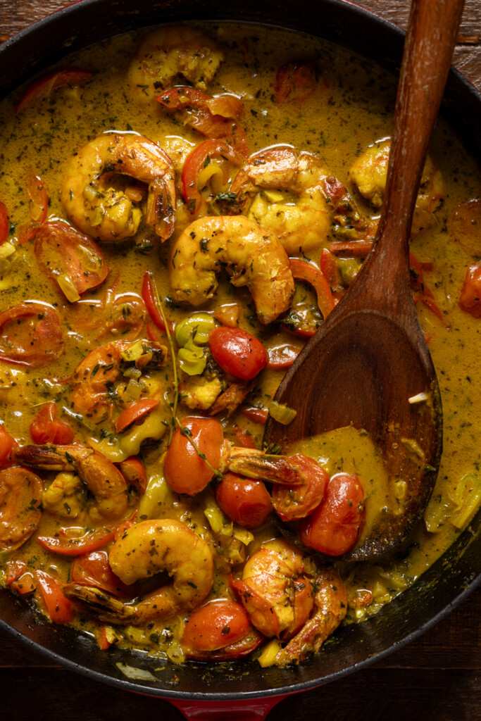 Up close shot of curry shrimp with a wooden spoon.