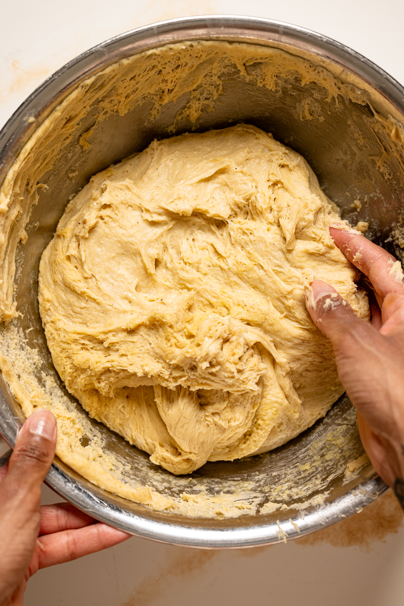 Shot of dough being held in a silver bowl.