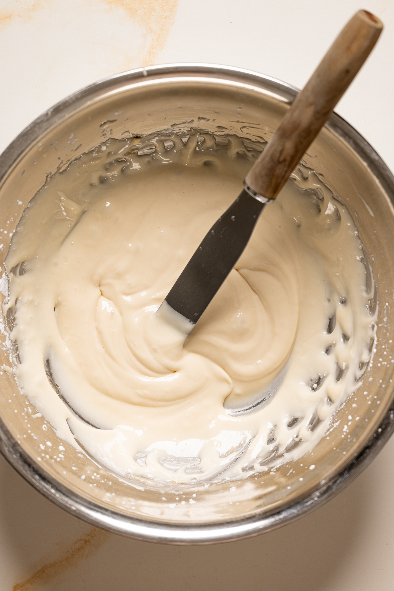 Glaze in a silver bowl with a spatula. 