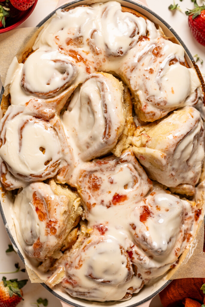 Strawberry shortcake cinnamon rolls in a baking dish with strawberries.