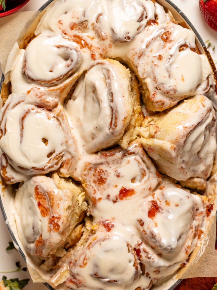 Strawberry shortcake cinnamon rolls in a baking dish with strawberries.