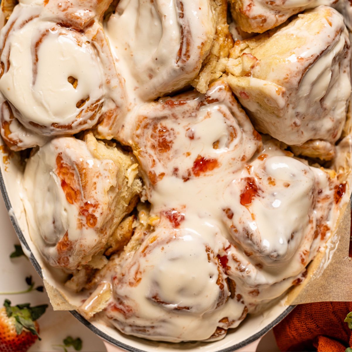 Strawberry shortcake cinnamon rolls in a baking dish with strawberries.